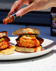 Sauce Boss Gang travel size smoky chipotle hot sauce pouring on a chicken biscuit.