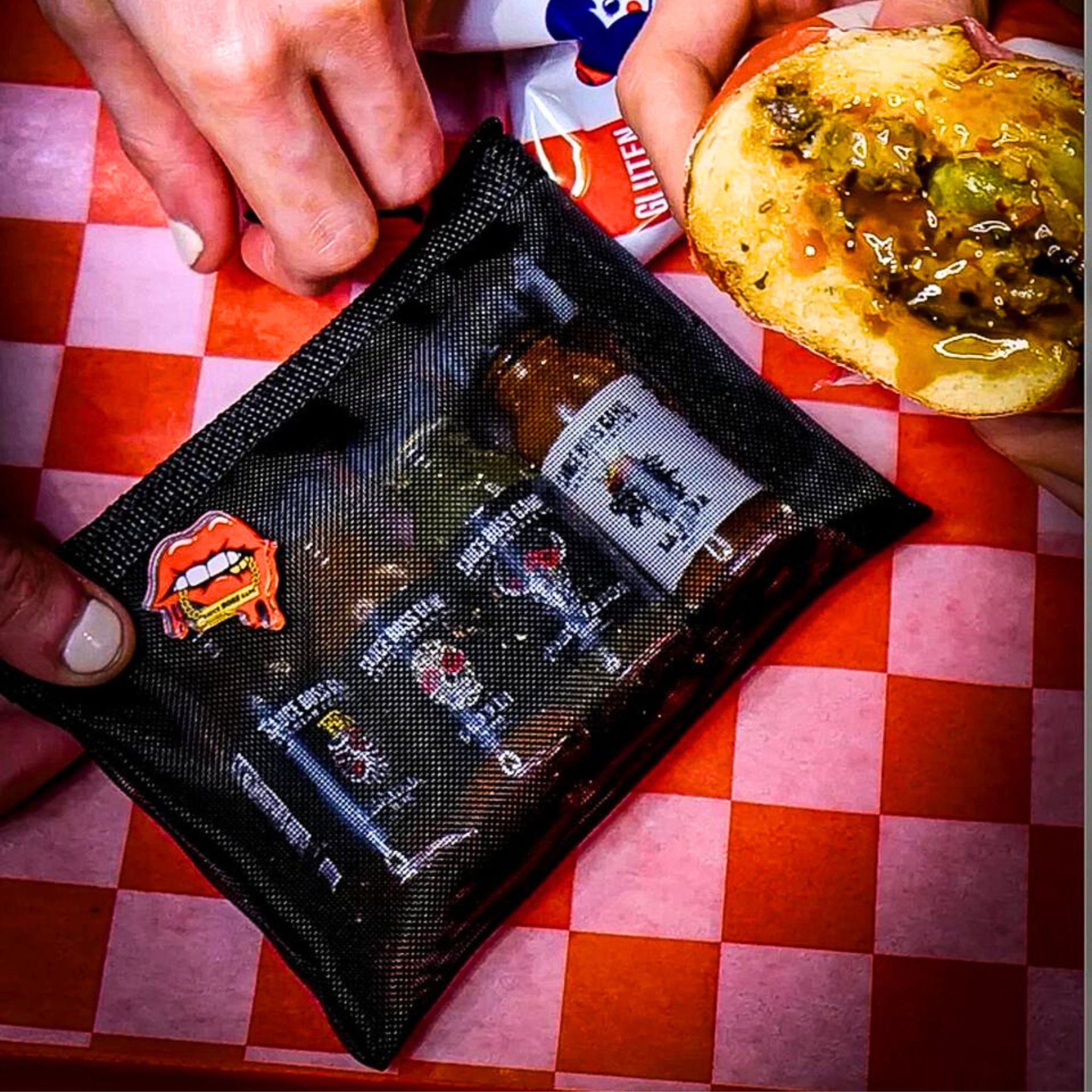 Sauce Boss Gang travel size hot sauce  travel pouch on a table with a sandwich.