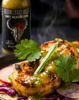 Grilled shrimp taco with jalapeno sauce and a bottle of Sauce Boss Gang sauce in the background.