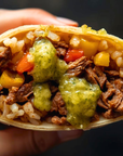 Close-up of a taco filled with meat, rice, and vegetables on a dark background