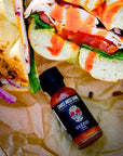 Sauce Boss Gang travel size garlic habanero hot sauce drizzled on a bagel sandwich.