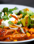  bowl of chili with avocado, sour cream, and cheese on a white plate