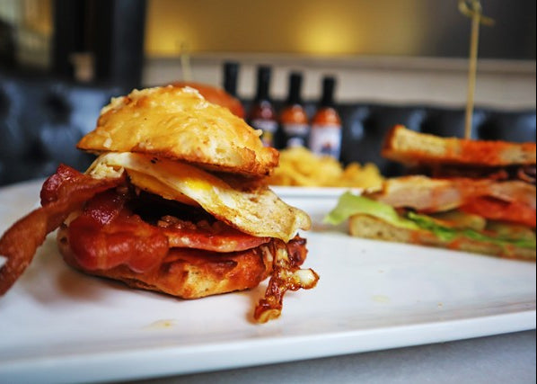 Stacked burger with bacon and egg on a white plate with a blurred background
