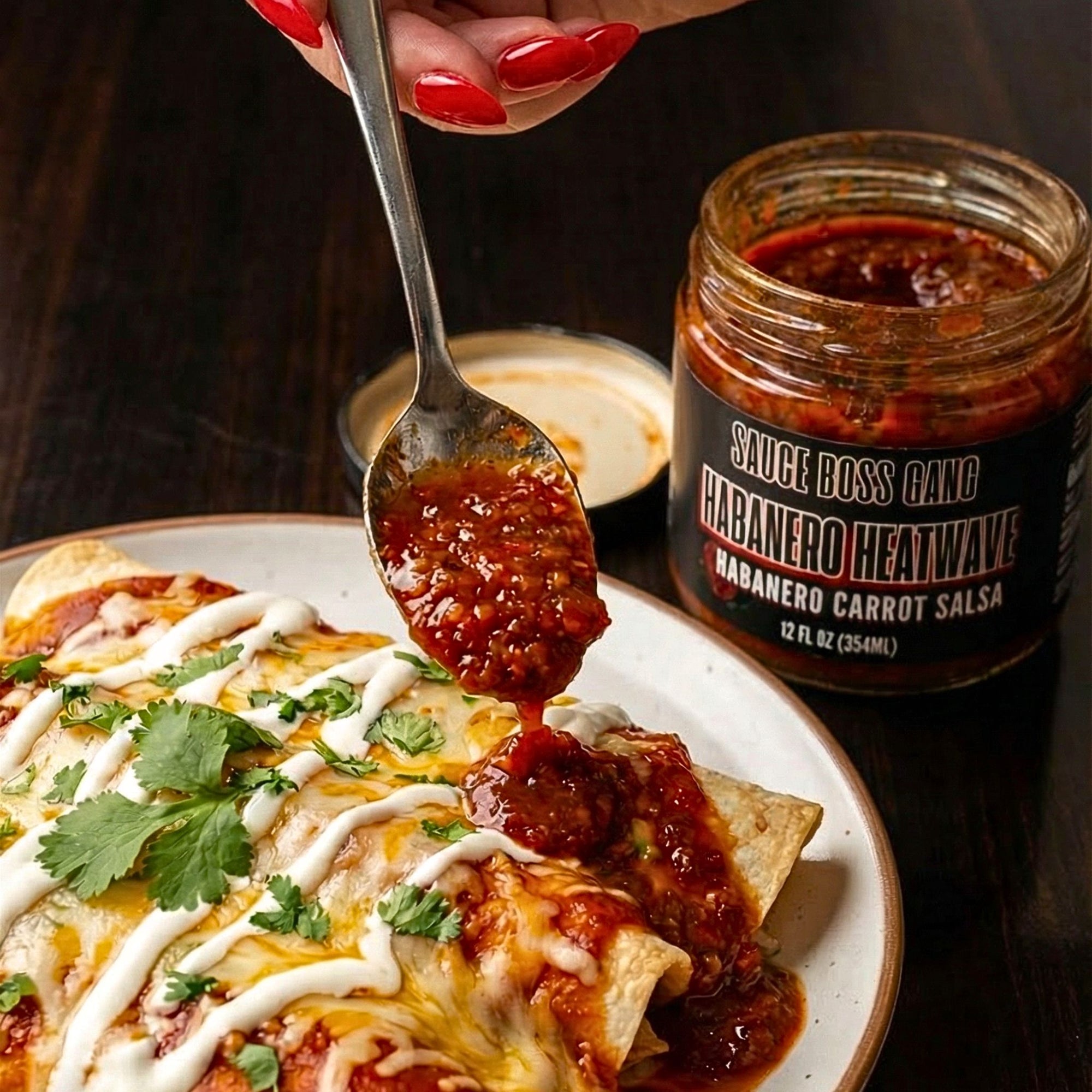 Spoonful of habanero salsa being added to enchiladas with a jar of Sauce Boss Gang Habanero Heatwave salsa.