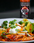 Plate of food with a bottle of La Jefa hot sauce in the background