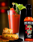 Sauce Boss Gang Garlic Habanero hot sauce infront of a bloody mary cocktail.