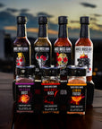 The whole gang hot sauce collection and the viva la noche seasoning collection front view at a restaurant at sunset.