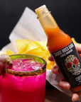 Sauce Boss Gang garlic habanero hot sauce in a pink dragonfruit margarita.