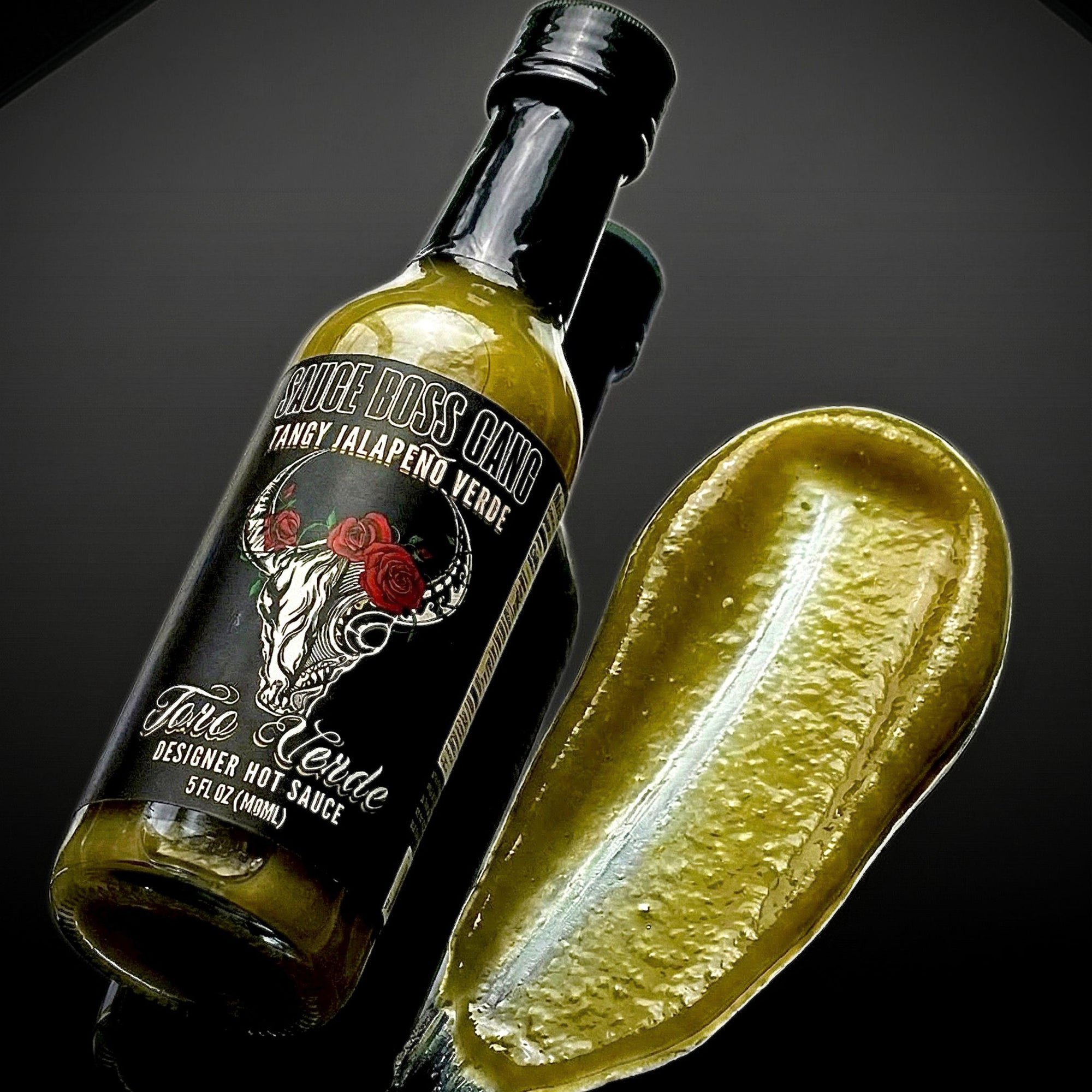 Hot sauce bottle with label featuring a bull and roses, next to a slice of lime on a dark background.