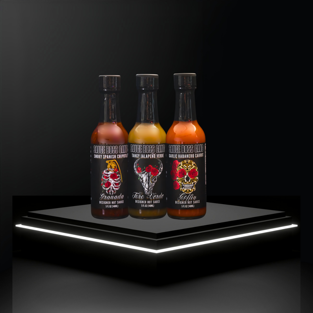 Three bottles of hot sauce on a black platform with a dark background
