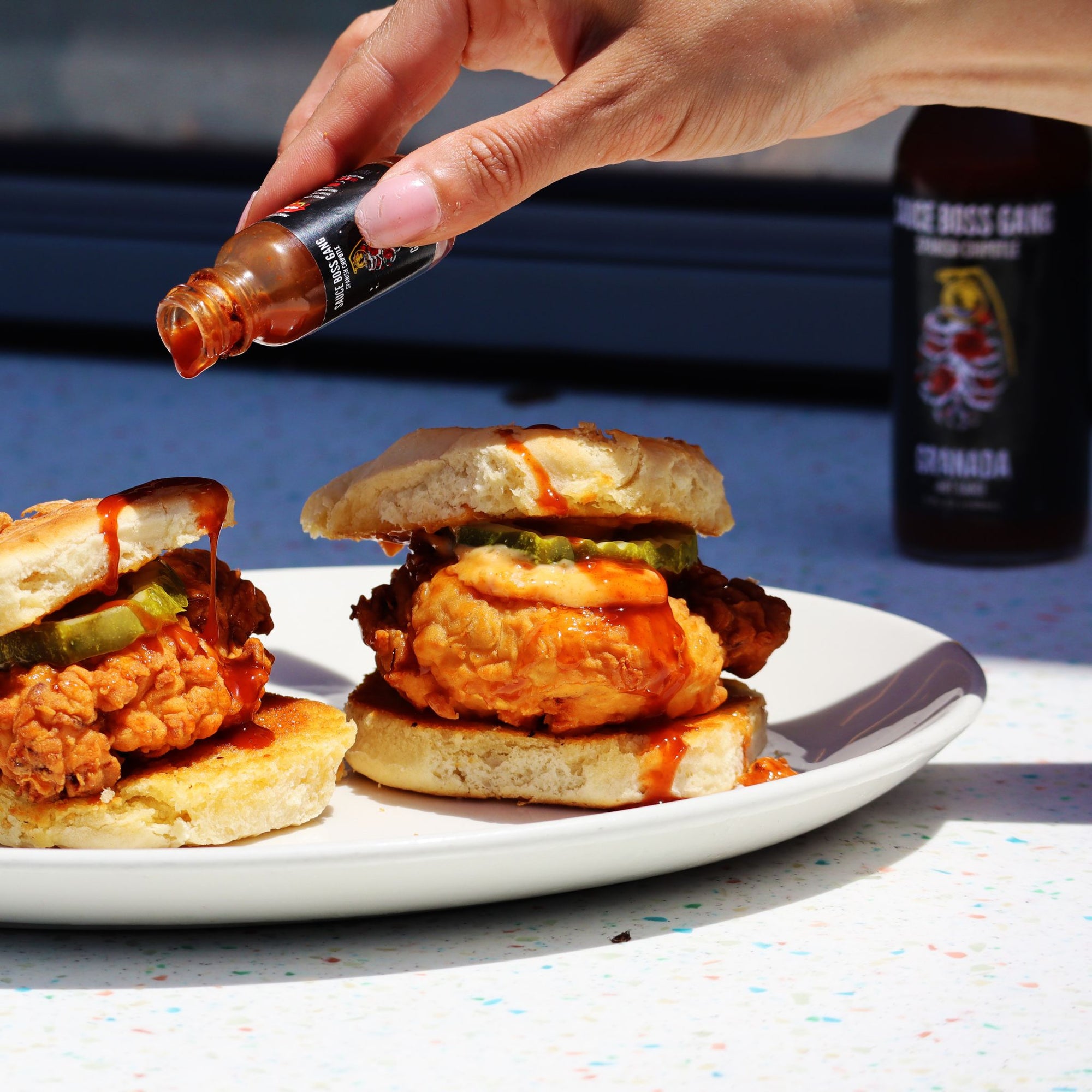 Sauce Boss Gang travel size smoky chipotle hot sauce pouring on a chicken biscuit.