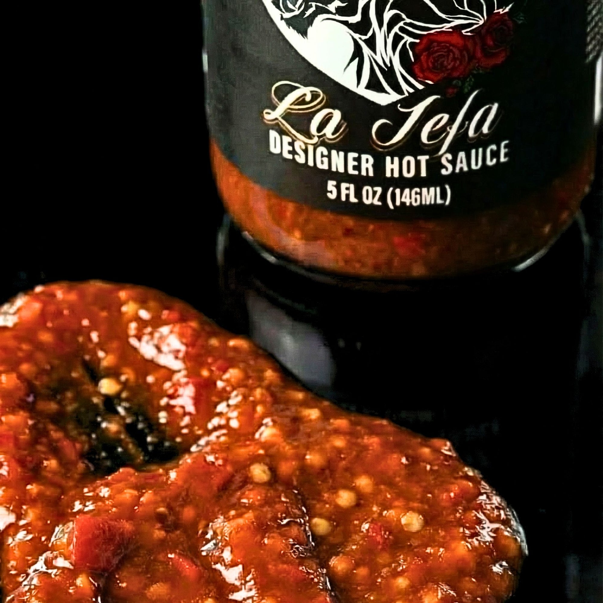 Bottle of La Jefa Designer Hot Sauce with a close-up of a pepper.