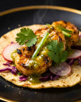 Tortilla with grilled shrimp, avocado, radish, and cilantro on a black plate.
