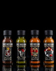 Four bottles of Sauce Boss Gang hot sauce with black caps on a reflective surface.
