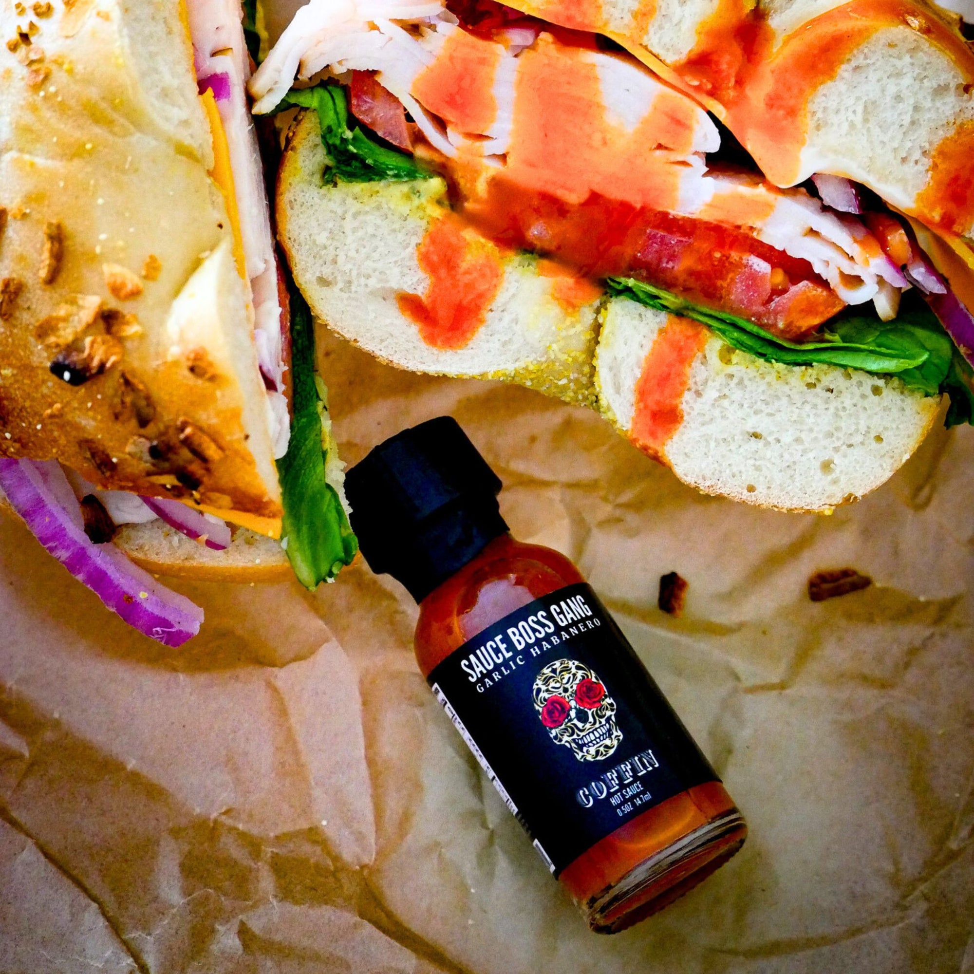 Sauce Boss Gang  travel size garlic habanero hot sauce drizzled on a bagel sandwich.