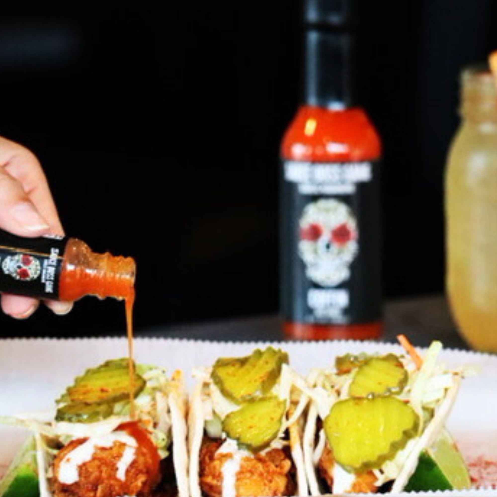 Travel sized garlic habanero hot sauce coffin habanero hot sauce pouring over tacos.