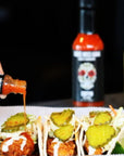 Travel sized garlic habanero hot sauce coffin habanero hot sauce pouring over tacos.